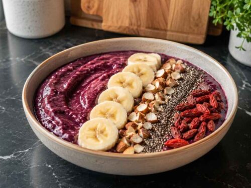 Fertige Acai-Smoothie-Bowl mit Bananenscheiben, Chiasamen und Gojibeeren in einer Schüssel