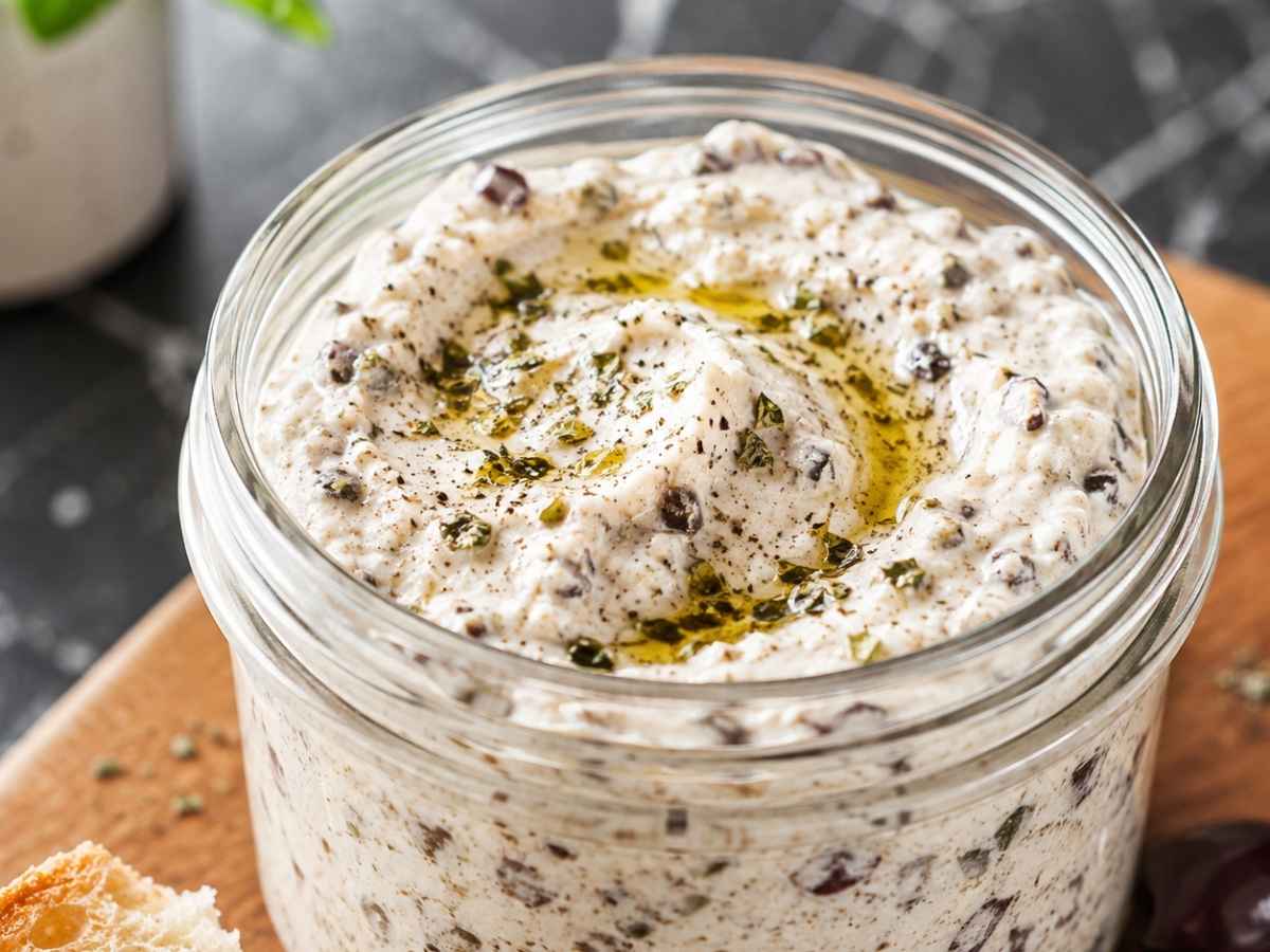 Nahaufnahme von cremigem Feta-Oliven-Aufstrich mit sichtbaren Olivenstückchen