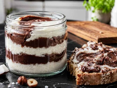 Zwei Gläser Kokos-Nougat-Aufstrich mit sichtbarer heller Kokos- und dunkler Nougatschicht
