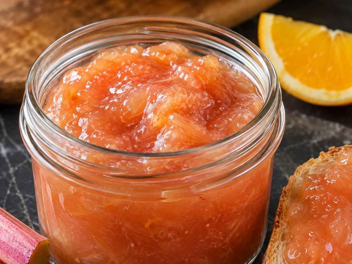 Rhabarber-Orangen-Konfitüre wird mit einem Messer auf ein Butterbrot gestrichen