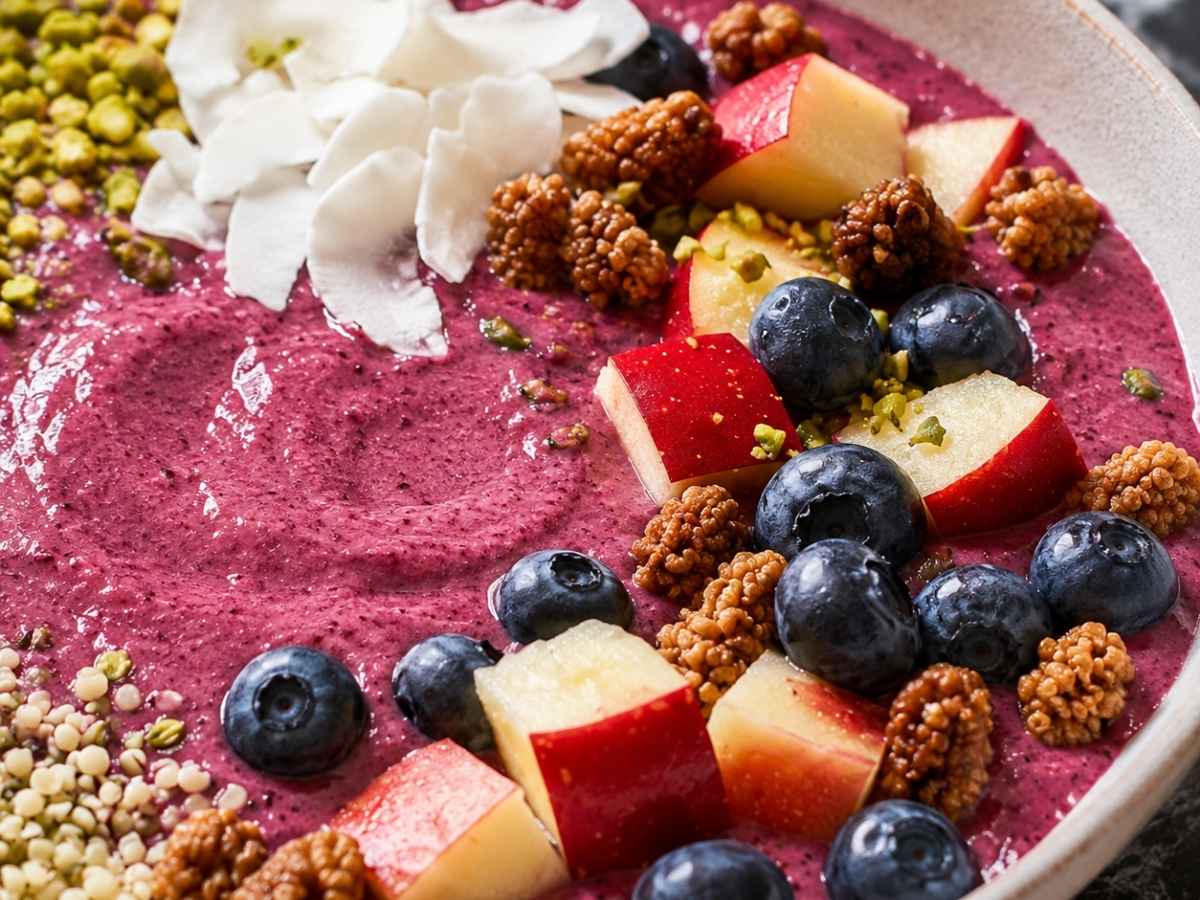 Detailansicht der cremigen Smoothie Bowl mit Maulbeeren, Pistazien, Kokoschips und frischen Heidelbeeren