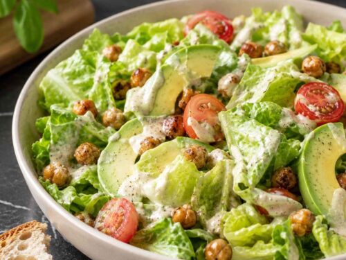 Nahaufnahme des cremigen Cashew-Dressings auf Römersalat mit knusprigen Kichererbsen und Avocadoscheiben