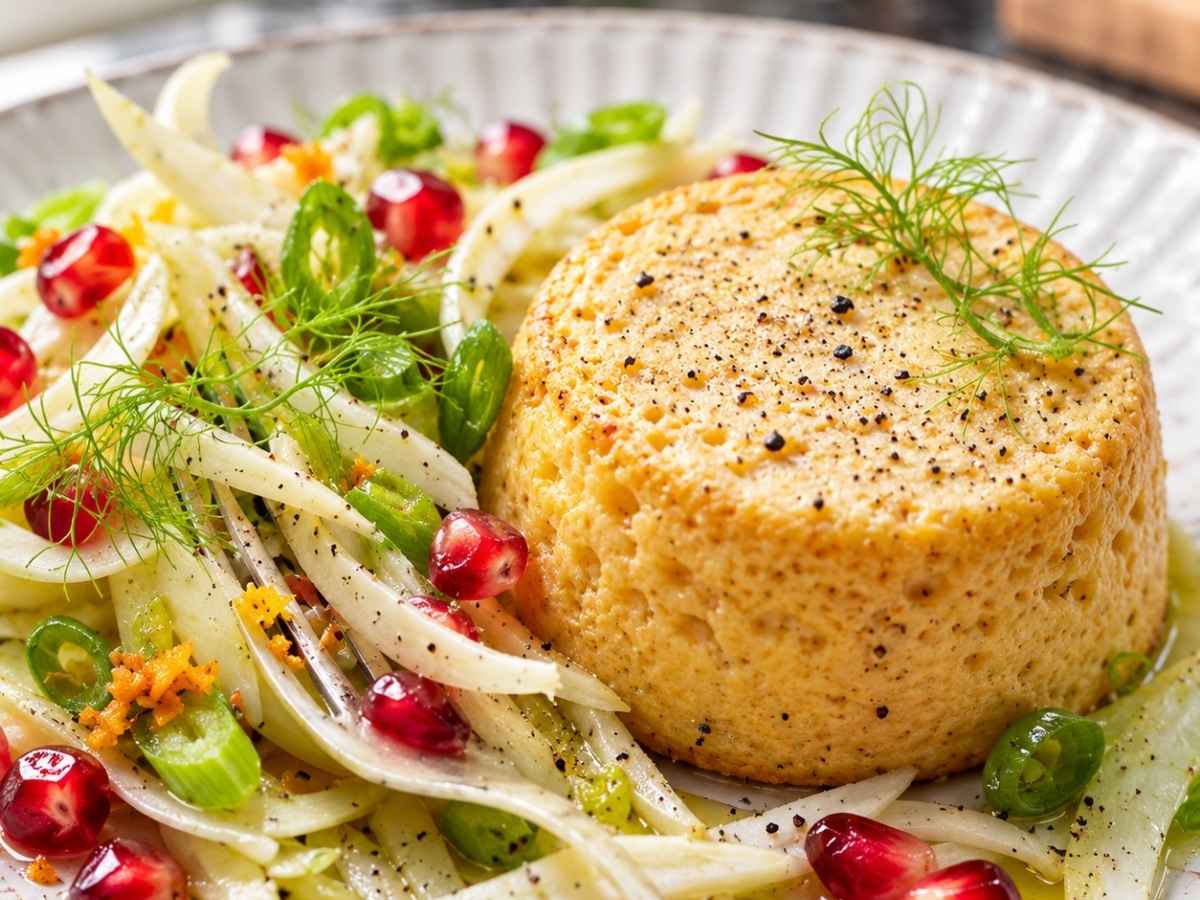 Nahaufnahme vom Cheddarsoufflé mit Fenchel-Granatapfel-Salat, orange gewürztes Käsesoufflé mit Fenchelstreifen und Fenchelgrün