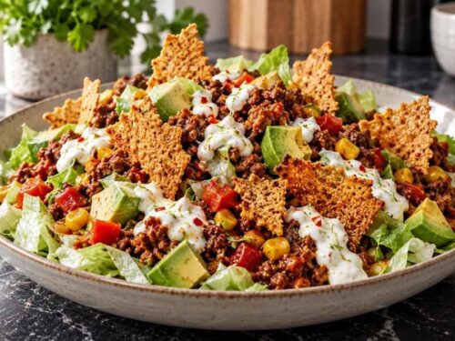 Tex-Mex-Salat mit Chili con Carne, Avocado, Limettencreme und Käse-Nachos in einer großen Schüssel